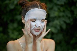 Beautiful woman With his eyes closed, touches his face with his hands white mask skin care photo