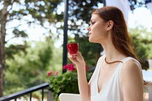 retrato de joven hermosa mujer con rojo taza de café al aire libre café verano día foto