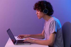 guy in headphones in front of laptop entertainment violet background photo