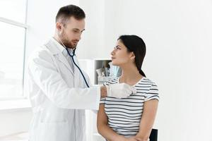 male doctor in white coat examining female patient in hospital photo
