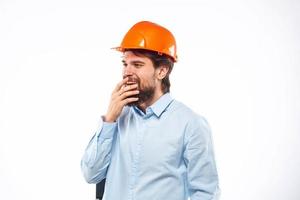 A man in an orange helmet shirt construction industry worked light background photo