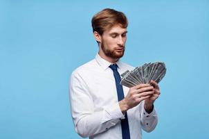 business man in shirt with tie holding money in hands wealth blue background photo