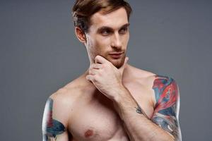 portrait of young man with tattoos on gray background and beautiful face model cropped view photo