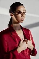 glamorous woman with jewelry and in a red jacket gesturing with her hands on a light background photo