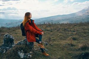 woman on nature in the mountains sits on a stone and autumn landscape photo