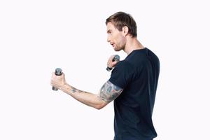 athlete with dumbbells is engaged in fitness on a light background indoors side view photo