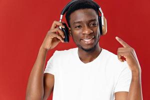 sonriente hombre de africano apariencia en auriculares muestra dedo tecnología foto