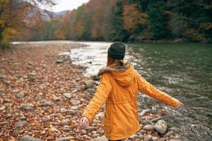 mujer camina a lo largo el río otoño bosque naturaleza montañas foto