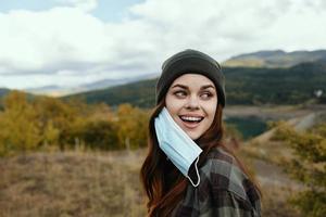 Energetic woman with a medical mask for a walk in nature in the autumn forest photo