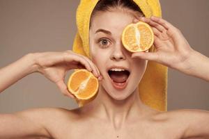 mujer en un amarillo toalla en su cabeza naranjas de cerca beige antecedentes foto
