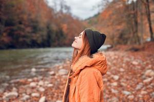 bonito mujer en otoño ropa en el bosque río caído hojas foto