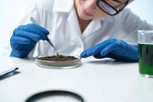 mujer en blanco Saco examina plantas microbiología profesional foto