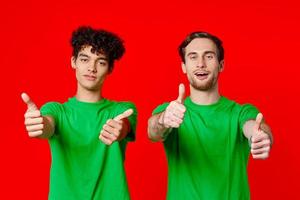dos alegre amigos desde verde camisetas gesticular con manos emociones foto