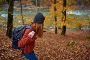 mujer con mochila viaje en otoño bosque foto