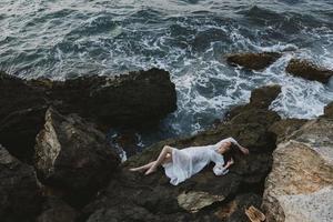 Beautiful bride in a secluded spot on a wild rocky coast in a white dress unaltered photo