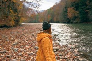 mujer camina a lo largo el río otoño bosque naturaleza montañas foto