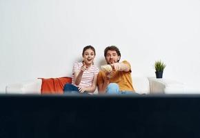 A man and a woman on the couch watching the TV indoors watching the show photo