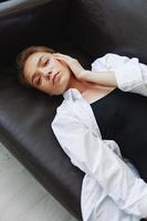 Women lying at home on the couch portrait with a short haircut in a white shirt, smile, depression in teenagers, home holiday photo