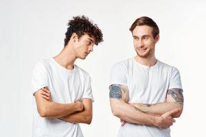 Two cheerful friends in white t-shirts stand side by side cropped view photo