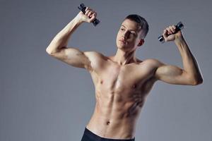 atlético muscular hombre con muscular cuerpo pesas en el manos de bíceps rutina de ejercicio foto