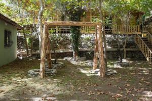 Wooden arbor in the garden of a house in the village. Wooden swing in the garden of a house in the village photo