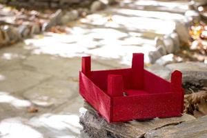 Red wooden basket on a stone in the garden. The red wooden box on a stone wall in the courtyard of the house photo