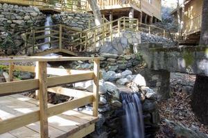 Waterfall in the park. Water cascades down the stairs. Waterfall in the forest with wooden stairs and railings in the mountains photo