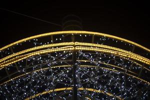 Garlands are arranged in arc. Urban decoration. Bright light bulbs. photo