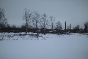 Winter landscape on cold day. Winter in Russia. View of field and factory. photo