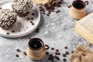 Roasted coffee beans in cup and cake on grey textured background photo