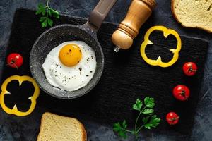 Fried eggs in a frying pan with fresh vegetables and spices. Concept for menu and advertising. photo