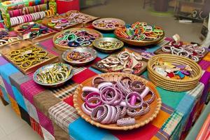 Variety colored handmade bangles are displayed with on some small baskets for sale. photo