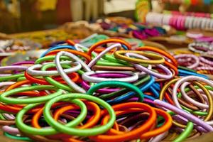 variedad de colores hecho a mano brazaletes son desplegado con en algunos pequeño cestas para venta. foto