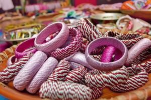 Variety colored handmade bangles are displayed with on some small baskets for sale. photo