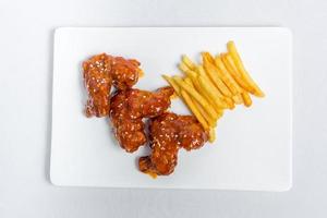 Spicy hot buffalo wings and french fries with white sauce on white plate isolated white background. Top views. photo