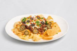 Mexican Famous Food Spicy Ground Beef Nachos. Heated crunchy tortilla chips with melted cheese and jalapeno served a snack food. photo