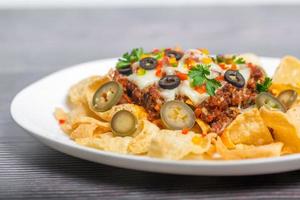 Mexican Famous Food Spicy Ground Beef Nachos. Heated crunchy tortilla chips with melted cheese and jalapeno served a snack food. photo