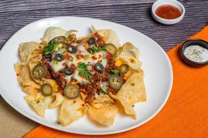 Mexican Famous Food Spicy Ground Beef Nachos. Heated crunchy tortilla chips with melted cheese and jalapeno served a snack food. photo