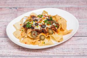 Mexican Famous Food Spicy Ground Beef Nachos. Heated crunchy tortilla chips with melted cheese and jalapeno served a snack food. photo