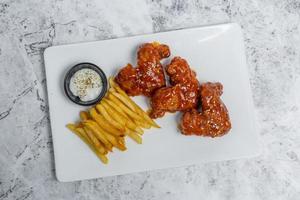 Hot and spicy buffalo chicken wings and crispy french fries with white sauce. photo