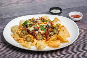 Mexican Famous Food Spicy Ground Beef Nachos. Heated crunchy tortilla chips with melted cheese and jalapeno served a snack food. photo