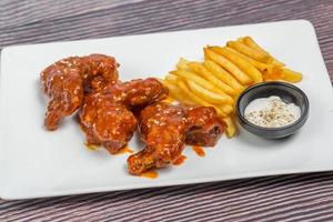 caliente y picante búfalo pollo alas y crujiente francés papas fritas con blanco salsa. foto