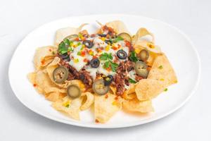 Mexican Famous Food Spicy Ground Beef Nachos. Heated crunchy tortilla chips with melted cheese and jalapeno served a snack food. photo