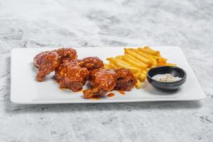 Hot and spicy buffalo chicken wings and crispy french fries with white sauce. photo