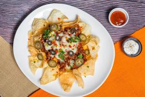 Mexican Famous Food Spicy Ground Beef Nachos. Heated crunchy tortilla chips with melted cheese and jalapeno served a snack food. photo