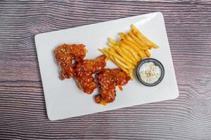 Hot and spicy buffalo chicken wings and crispy french fries with white sauce. photo