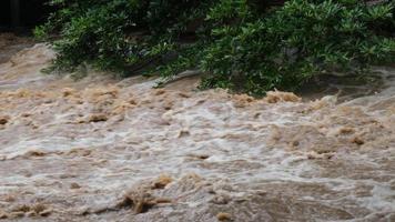 Waterfall cataract in forest mountains. Dirty streams are flowing down the mountain slopes of the mountain forest after heavy rains in Thailand. River flood, selective focus video