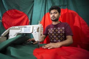 Bangladesh, December 09, 2017, Md Rashed Alam, a young tailor spends a busy time making Bangladeshi national flags ahead of Victory month near Gulistan, Dhaka. photo