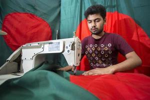 Bangladesh, December 09, 2017, Md Rashed Alam, a young tailor spends a busy time making Bangladeshi national flags ahead of Victory month near Gulistan, Dhaka. photo