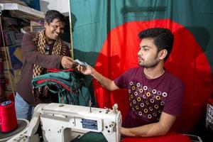 Bangladesh, December 09, 2017, A buyer buying a newly sewn Bangladeshi red green flag ahead of Victory month near Gulistan at Dhaka. photo